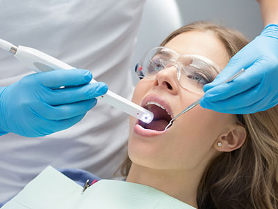 An image of a dental professional using a high-tech device to clean a patient s teeth during a dental appointment.